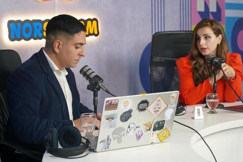 Dos personas grabando una entrevista en el estudio de Norstream, con el logotipo iluminado de fondo